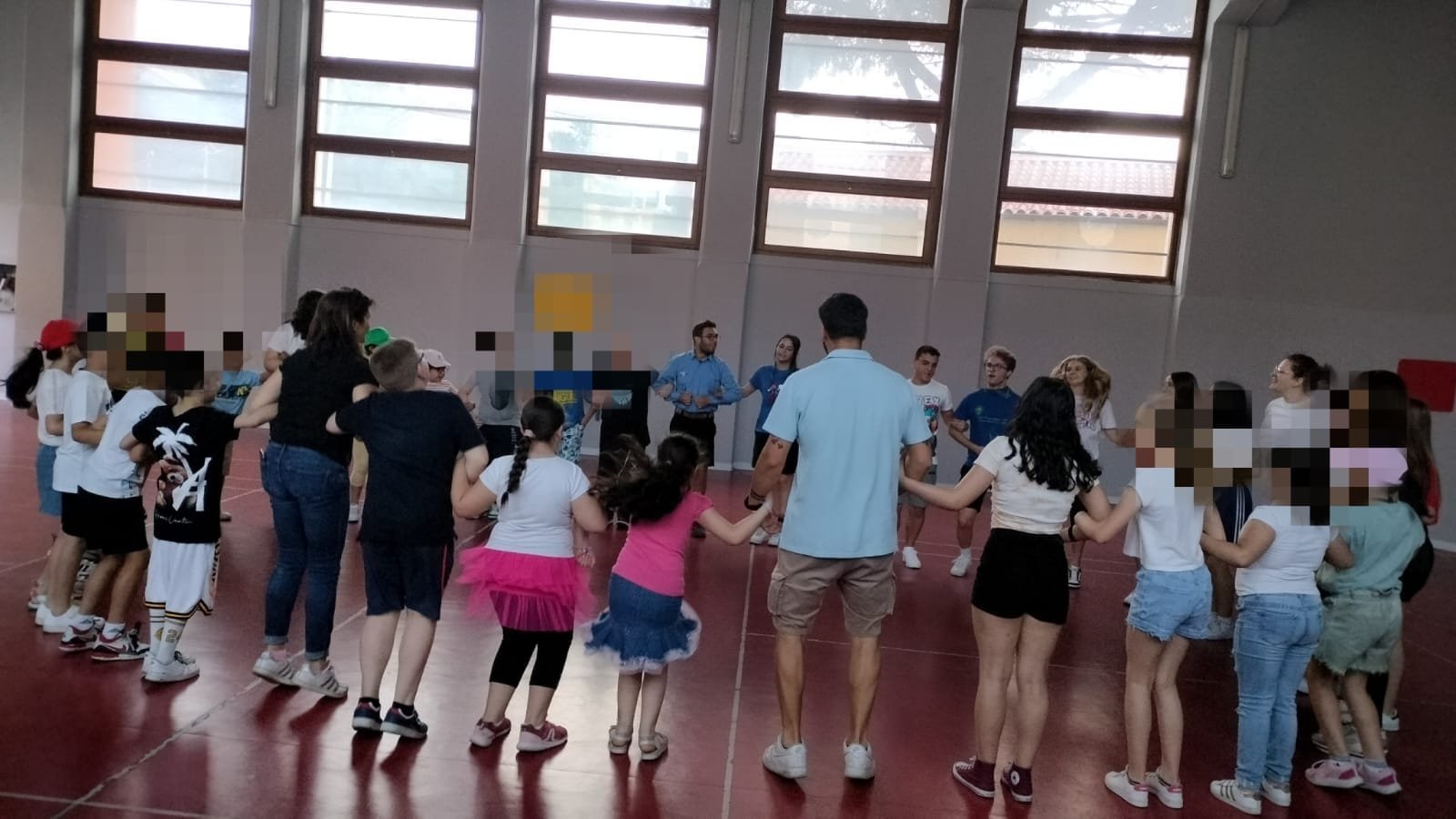Volontari e bambini giocano insieme in cerchio in palestra